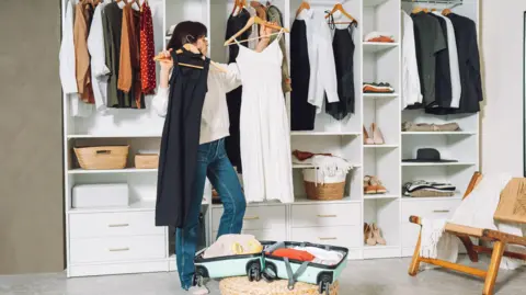 Getty Images Mujeres empacando trajes para viajes en el camerino 