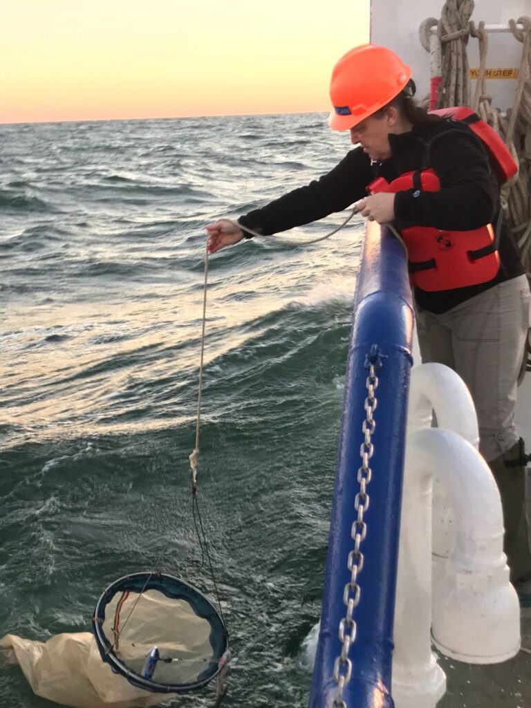 Schnetzer, con un casco de color naranja brillante, se para en el barco y deja caer la red al agua.
